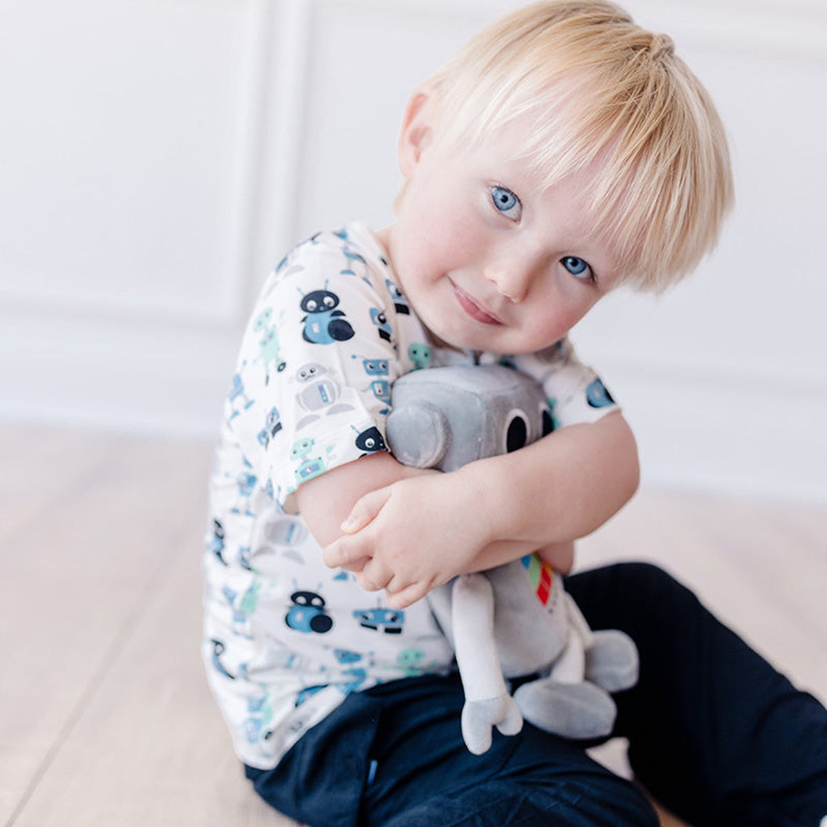 ロボット柄の半袖クルーネックTシャツを着て、ぬいぐるみを抱く子ども