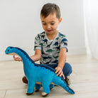 Dove Dino Museumの恐竜柄半袖クルーネックTシャツを着て、青い恐竜のぬいぐるみと遊ぶモデル