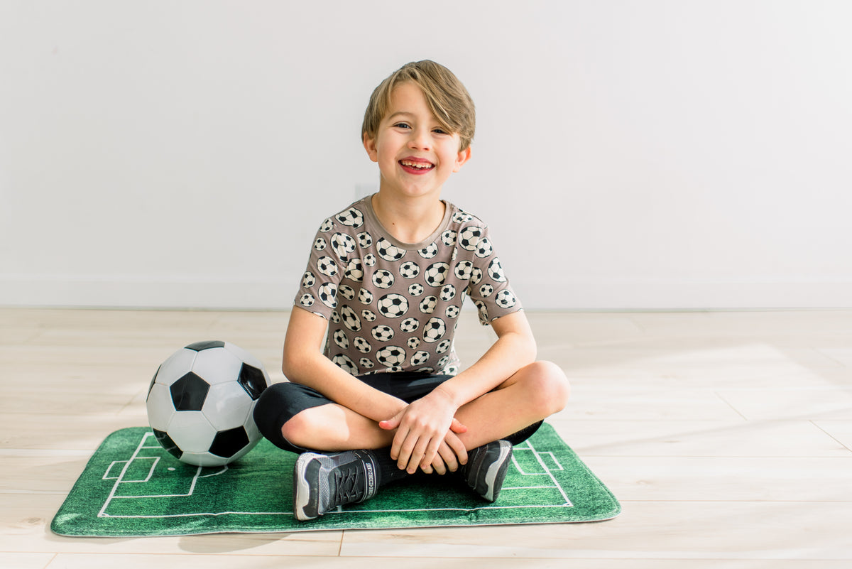 Portabella Soccer柄の半袖クルーネックTシャツを着て座る子どもの正面