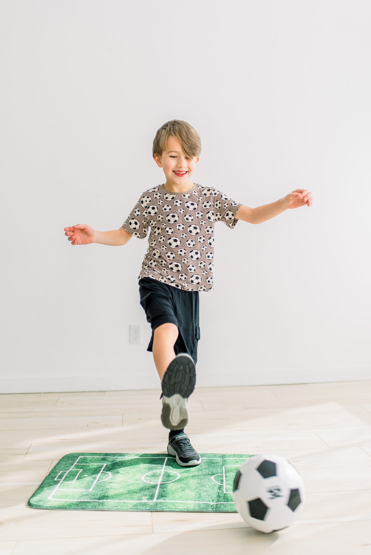 Portabella Soccer柄の半袖クルーネックTシャツを着てボールを蹴る子どもの全身