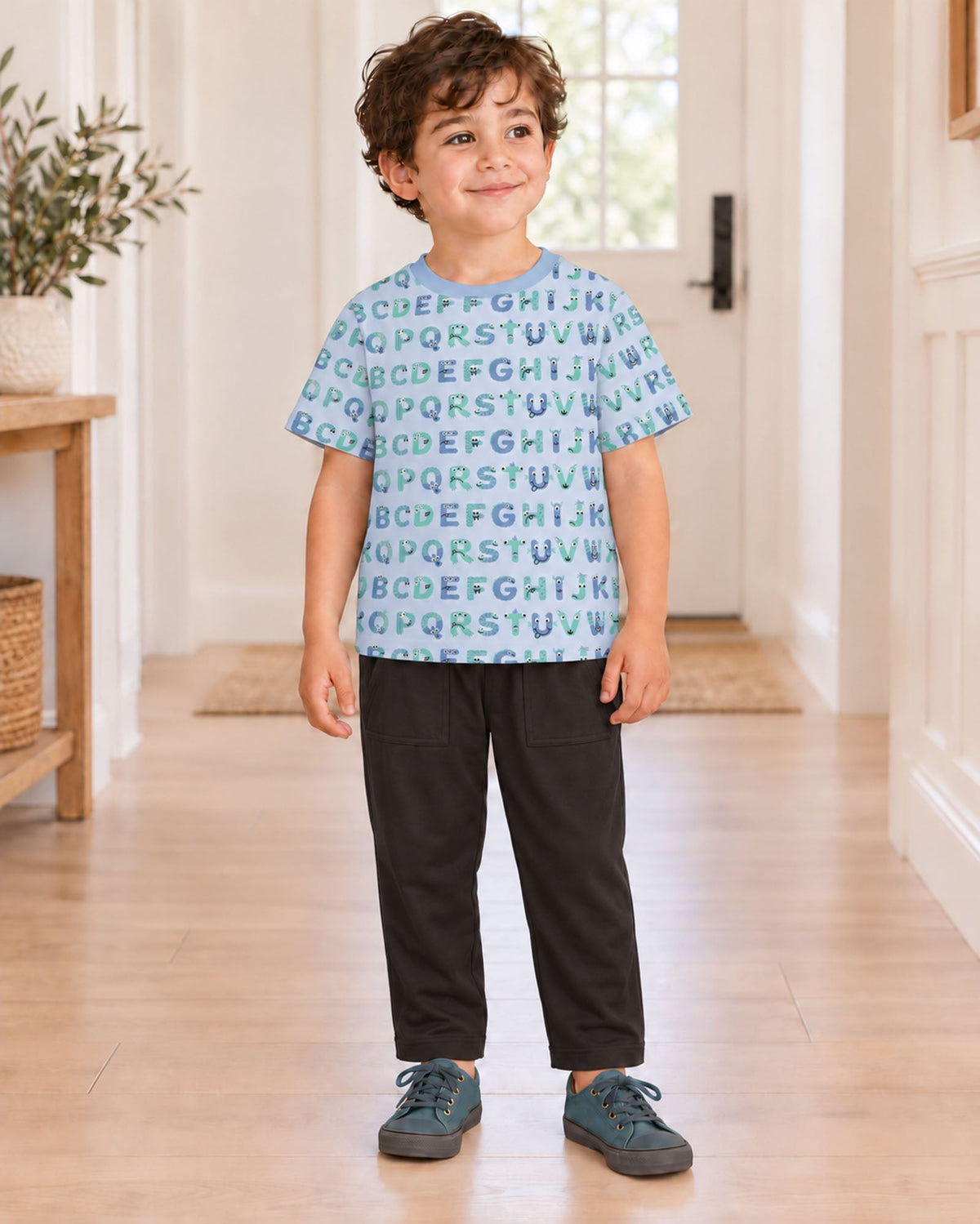 Dew ABC Monstersのアルファベット柄半袖クルーネックTシャツを着て、室内に立つモデルの全身