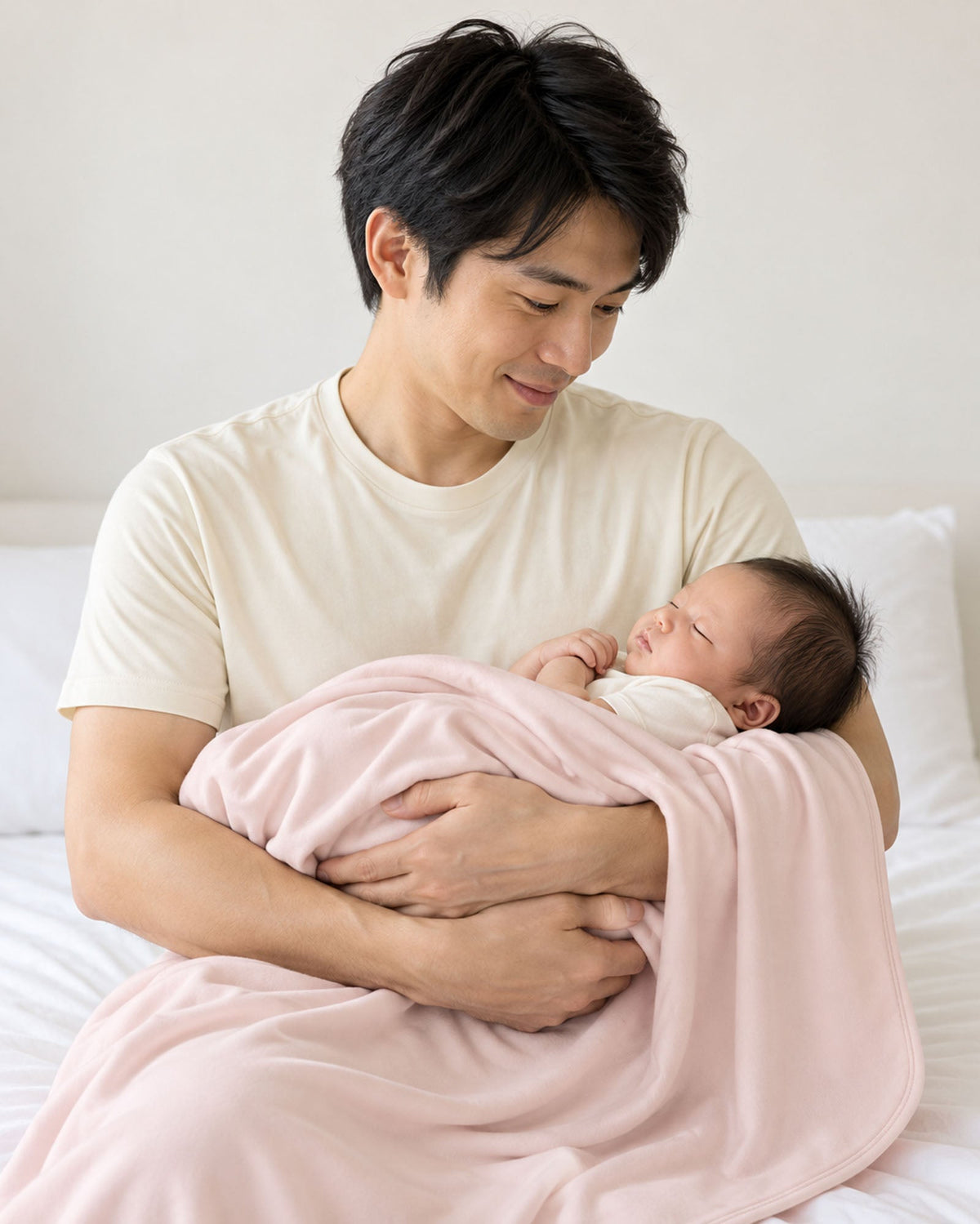 マカロンのレシービングブランケットに包まれ、大人に抱っこされる赤ちゃん