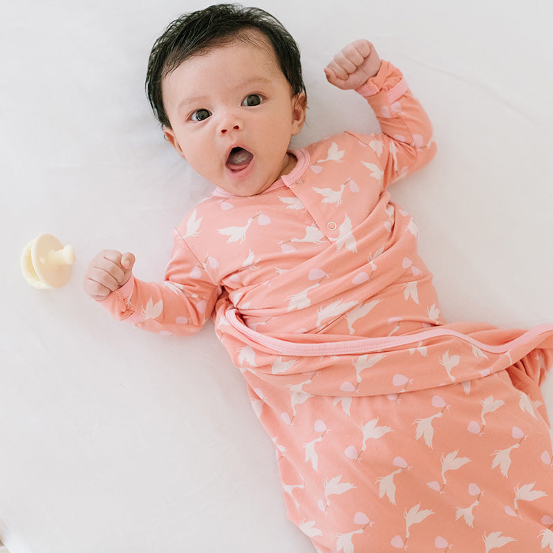 ブラッシュのコウノトリ柄の服と、同柄のレシービングブランケットを合わせた赤ちゃん。